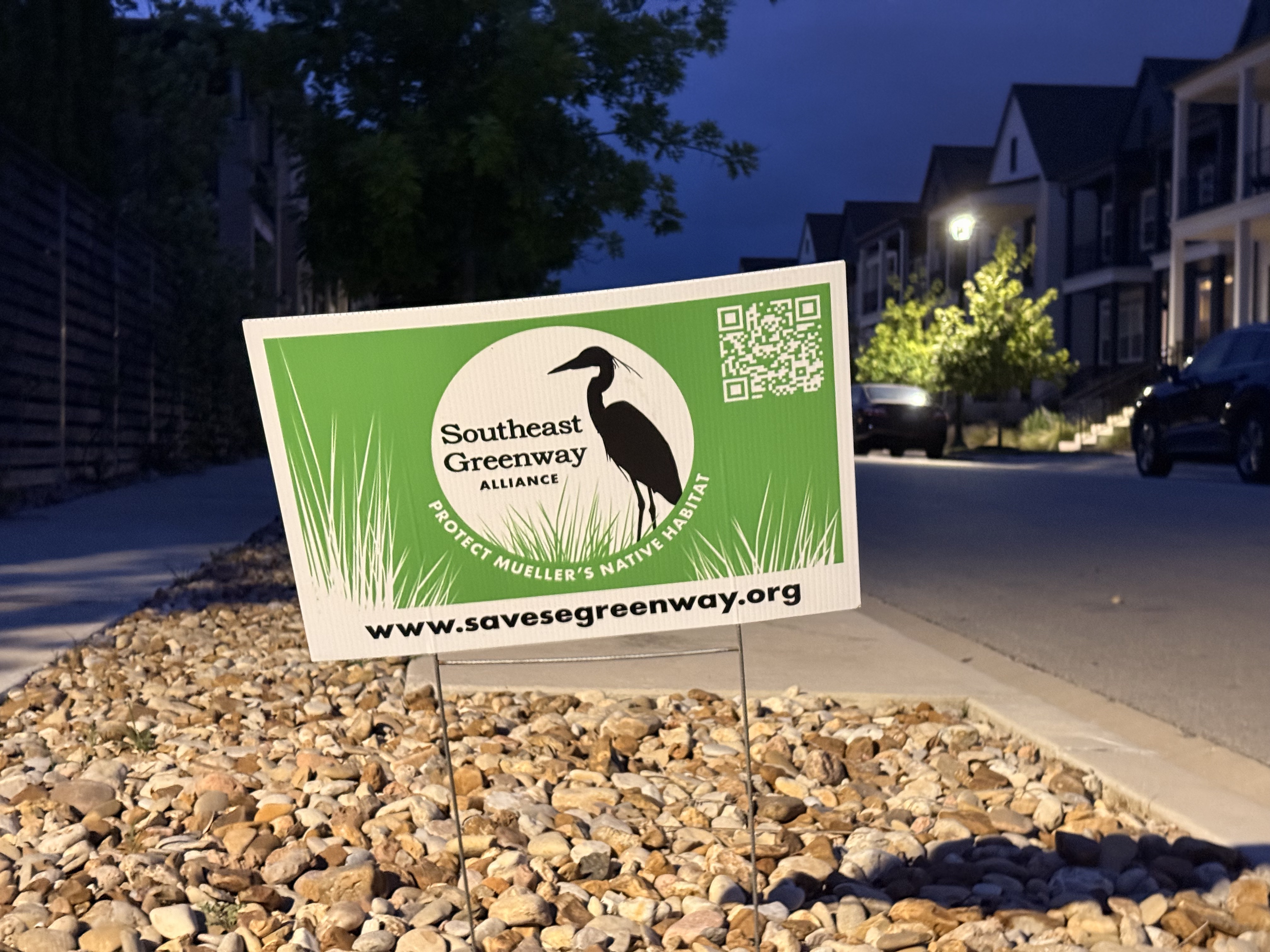Southeast Greenway Alliance yard sign in rock garden in front of Mueller townhomes